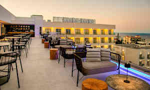 Takbar med sitteplasser og utsikt over sjøen og hotellbygninger. (AI-generert tekst)