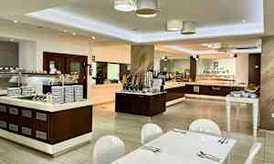 Interiør av en bufférestaurant med serveringsområder og bord. (AI-generert tekst)