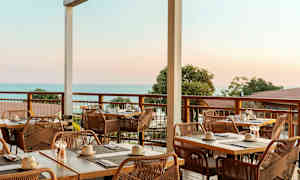 Uteservering med dekkede bord og utsikt mot havet. (AI-generert tekst)