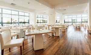 En moderne og lys restaurant med store vinduer og dekkede bord. (AI-generert tekst)