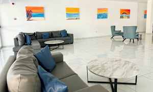 En hotelllobby med sofaer og lenestoler, veggene dekorert med malerier. (AI-generert tekst)