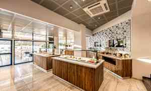 Et moderne og lyst buffetområde med mat servert på trestasjoner og en dekorert flislagt vegg. (AI-generert tekst)