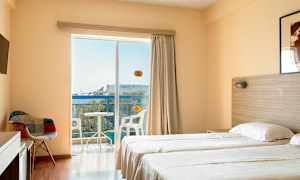 Et hotellrom med to enkeltsenger, en stol, TV, og en balkong med utsikt. (AI-generert tekst)