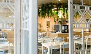 En restaurant med bord og stoler, samt en dekorert buffet og hengende grønt. (AI-generert tekst)