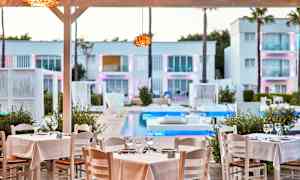 Restaurantbord med hvite duker ved et basseng, omgitt av moderne arkitektur. (AI-generert tekst)