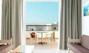 Et hotellrom med utsikt over en balkong med et bord og stoler. (AI-generert tekst)