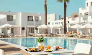 En frokost servert ved et bord med utsikt over et basseng og solsenger. (AI-generert tekst)