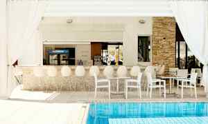 Utendørs bar med hvite stoler og bord ved et basseng. (AI-generert tekst)