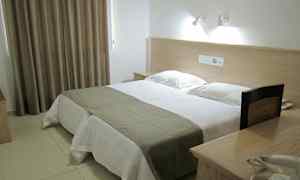 Et hotellrom med en dobbeltseng, sengelamper og et bord med telefon. (AI-generert tekst)