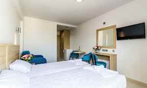 Hotellrom med seng, bord, stol, speil og TV. (AI-generert tekst)