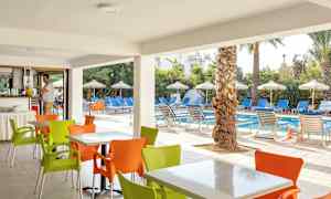 Utendørs servering med fargerike stoler foran et basseng med solsenger og parasoller. (AI-generert tekst)