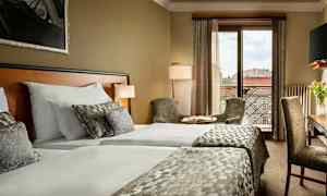 Hotellrom med to senger, sitteplasser og utsikt over byen. (AI-generert tekst)