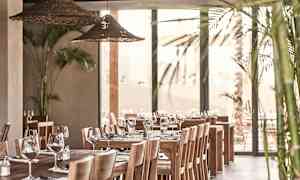 Interiør av en restaurant med trebord, stoler og dekorert med glass og bestikk. (AI-generert tekst)