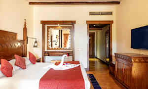 Et hotellrom med en dobbeltseng med røde puter og en dekorasjon formet som en svane på sengen. (AI-generert tekst)