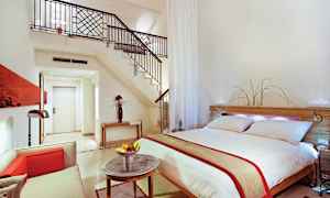 Moderne innredet hotellrom med dobbeltseng, sittegruppe og trapp til loft. (AI-generert tekst)