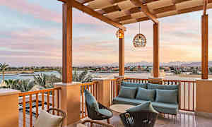 Terrasse med sofagruppe og utsikt over en kanal og bygninger i solnedgang. (AI-generert tekst)