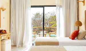 Et hotellrom med dobbeltsenger og en glassdør som fører ut til en balkong. (AI-generert tekst)