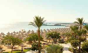 Strand med parasoller og palmer ved havet. (AI-generert tekst)