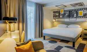 Hotellrom med stor seng, skrivebord og sitteplass. (AI-generert tekst)