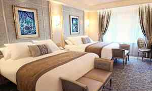 Luksuriøst innredet hotellrom med to dobbeltsenger, elegante møbler og veggdekorasjoner. (AI-generert tekst)