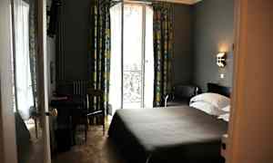 Et hotellrom med en dobbeltseng, et bord og en stol, samt en glassdør med utsikt og gardiner. (AI-generert tekst)