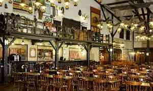 Interiør av en rustikk restaurant med trebord og stoler samt dekorasjoner på veggene. (AI-generert tekst)