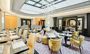 En elegant restaurant med store vinduer og en fantastisk krystallkrone. (AI-generert tekst)