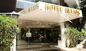 Inngangen til hotellet Hotel Helios med navnet skrevet over inngangen. (AI-generert tekst)