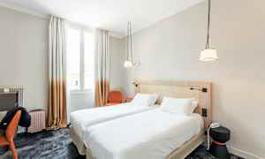 Et hotellrom med to enkeltsenger koblet sammen, et skrivebord, en stol og et lysinnslippende vindu. (AI-generert tekst)