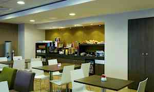 Frokostrom med bord og stoler og en buffet med forskjellige matvarer. (AI-generert tekst)