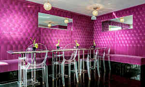 En moderne og fargerik restaurant eller lounge med fuschiafargede veggpaneler, gjennomsiktige stoler og speildekorasjoner. (AI-generert tekst)