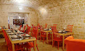 Spisesal med steinhvelv, røde stoler og dekkede bord. (AI-generert tekst)