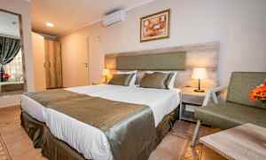 Hotellrom med to senger, sengetøy og nattbord med lampe. (AI-generert tekst)