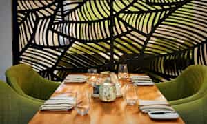 Et dekket bord med grønne stoler og en dekorativ skjerm i bakgrunnen. (AI-generert tekst)