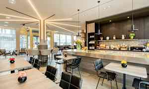 Moderne kafémiljø med sitteplasser ved bord og bardisk, dekorert med blomster. (AI-generert tekst)