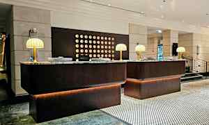 En resepsjonsdisk i en hotellobby, med marmortopper og bordlamper. (AI-generert tekst)