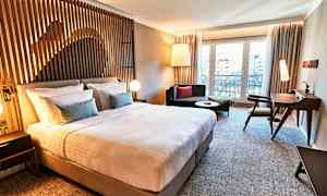 Et moderne hotellrom med en stor seng, sitteplasser og skrivebord. (AI-generert tekst)