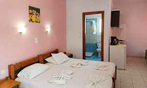 Et enkelt hotellrom med rosa vegger, to enkeltsenger og utsikt mot baderomsdøren. (AI-generert tekst)