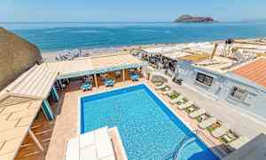 Bilde av et utendørs svømmebasseng med solsenger, restaurantområde og havutsikt i bakgrunnen. (AI-generert tekst)