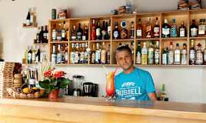 En bar med hyller fylt med flasker med alkohol og et serveringsområde med en fargerik drink. (AI-generert tekst)