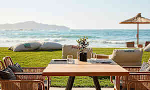 Et bord med stoler på en terrasse med utsikt over sjøen. (AI-generert tekst)