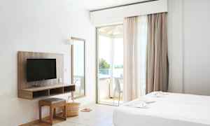 Et hotellrom med to senger, en TV, et speil og en balkong. (AI-generert tekst)