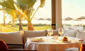 Et dekket bord på en restaurant med mat og glass og en solrik utsikt med palmer. (AI-generert tekst)