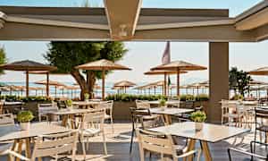 Uteservering med utsikt mot en strand og parasoller. (AI-generert tekst)