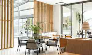 Interiør av et moderne rom med bord, stoler og vinduer. (AI-generert tekst)