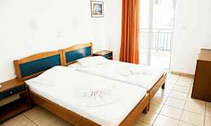 To enkeltsenger i et lyst rom med et bilde på veggen og en balkong med oransje gardiner. (AI-generert tekst)