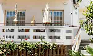 Terrasse med parasoller og utemøbler ved en lys bygning. (AI-generert tekst)