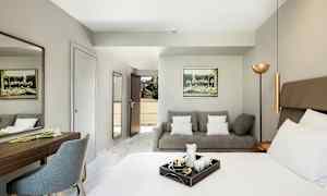 Et hotellrom med en seng, en sofa og et skrivebord. (AI-generert tekst)