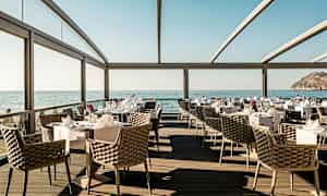 Restaurant med havutsikt, elegante møbler og dekkede bord. (AI-generert tekst)