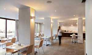 Lyst og moderne spisestue med hvite bord og lyse trestoler. (AI-generert tekst)